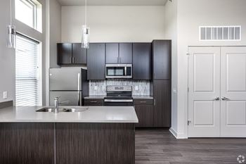 A modern kitchen with dark wood cabinets and a white countertop.